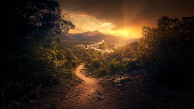 Sendero entre colinas hacia un pueblo, al atardecer